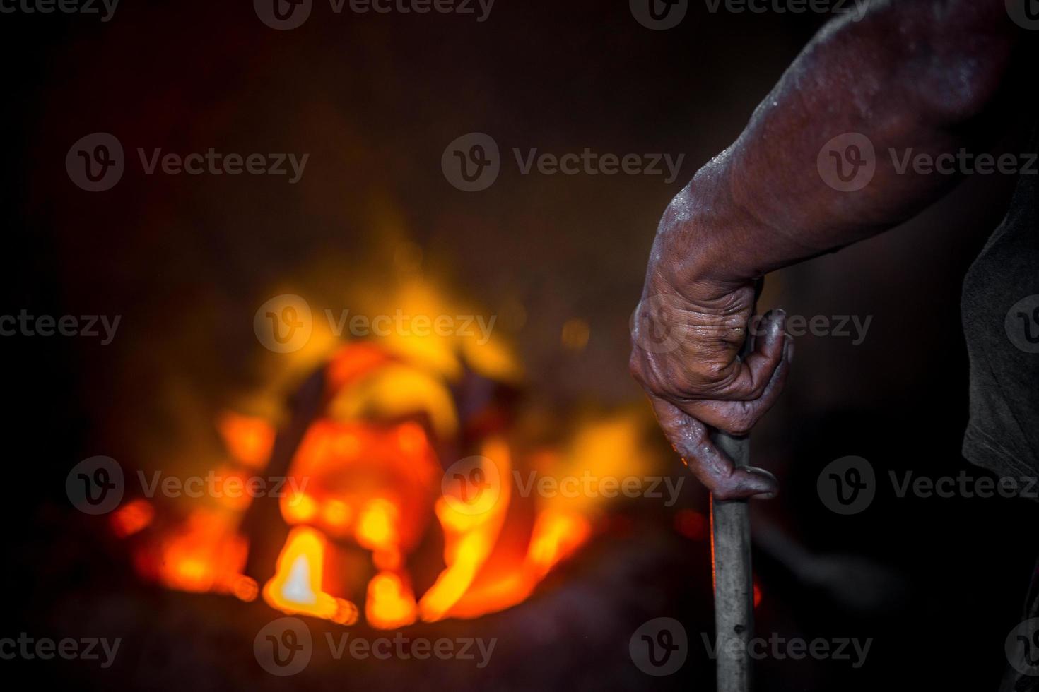 Unsafe worker hands. A local steel machine parts making yard worker melting scrap on hot furnace. photo