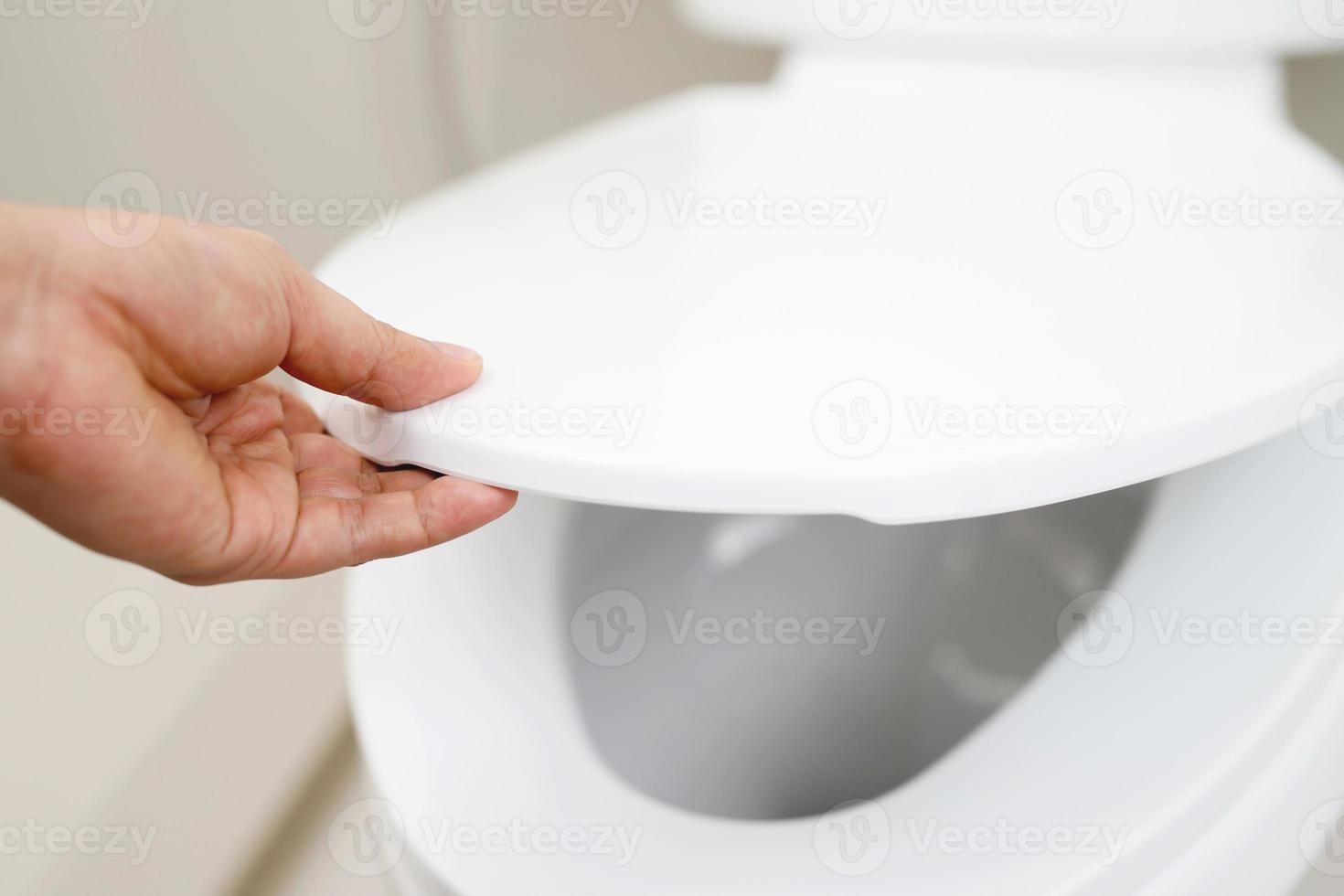 close up hand of a woman closing the lid of a toilet seat. Hygiene and