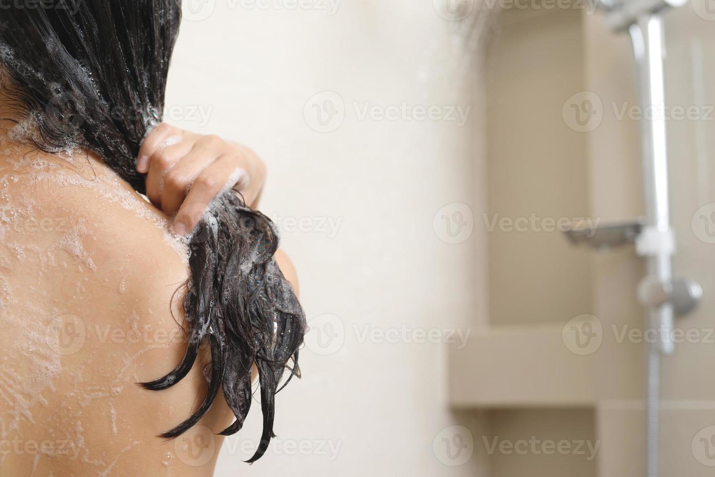 woman taking shower and washing hair with shampoo photo