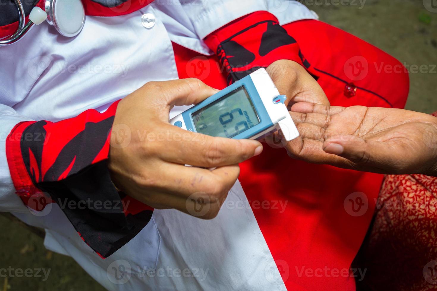 Woman checking sugar level with glucometer using a blood sample at Narsingdi, Bangladesh. Learn to use a glucometer. Concept of diabetes treatment. photo