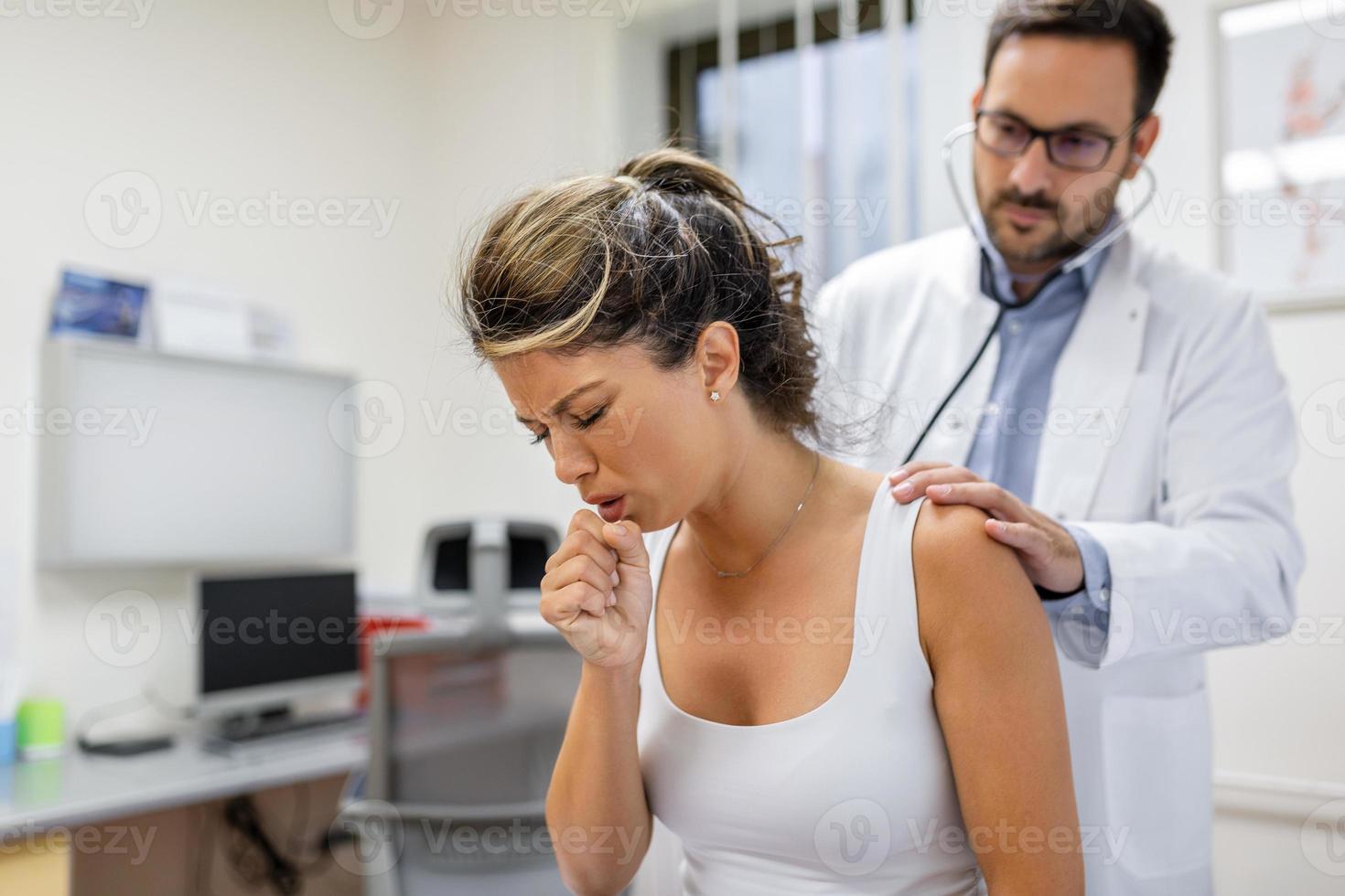 Young female patient in the clinic suffered from pneumonia, she is coughing the doctor listens to the wheezing in the lungs with a stethoscope. photo