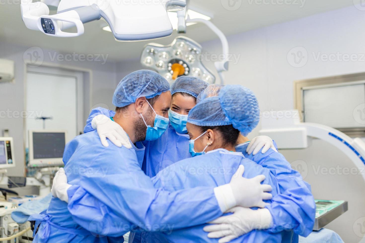Partial view of hard-working male and female hospital team in full protective wear standing together in group embrace. photo