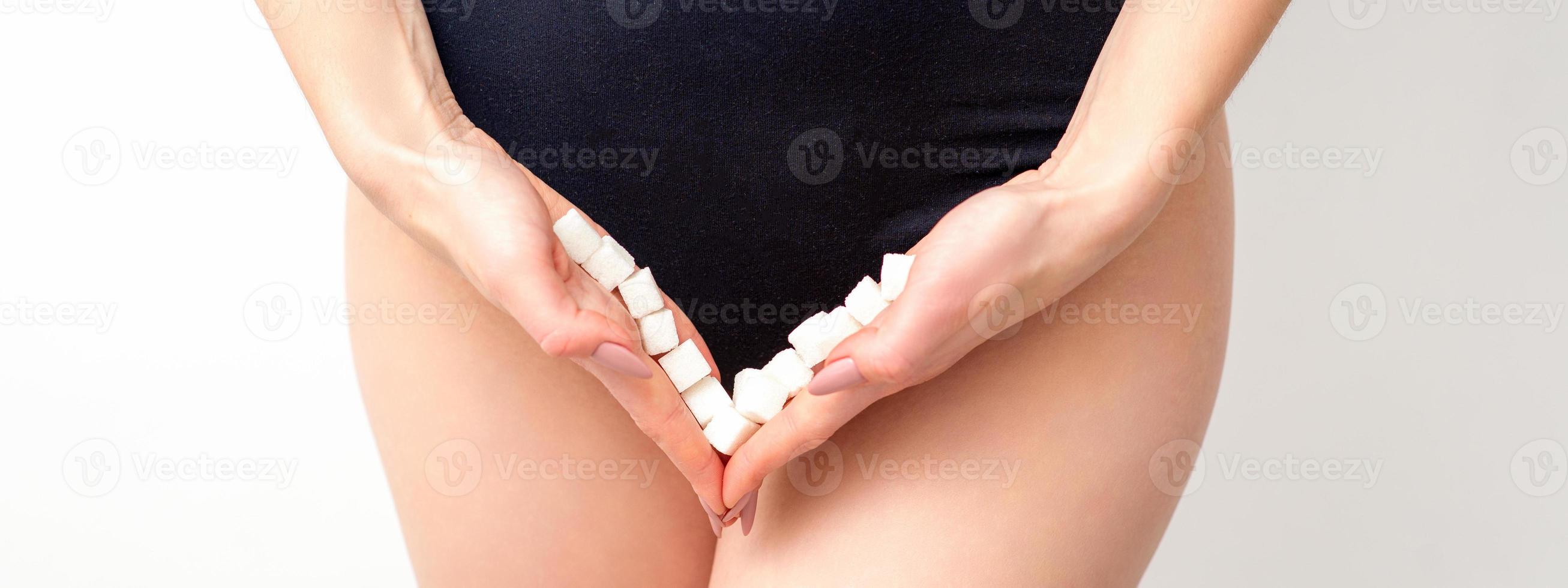 Woman holding sugar cubes on bikini zone, the concept of intimate depilation, problems of intimate hygiene. photo