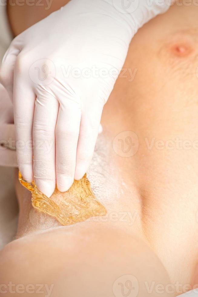 Young caucasian man receiving hair removal from his armpit in a beauty salon, depilation men's underarm. photo