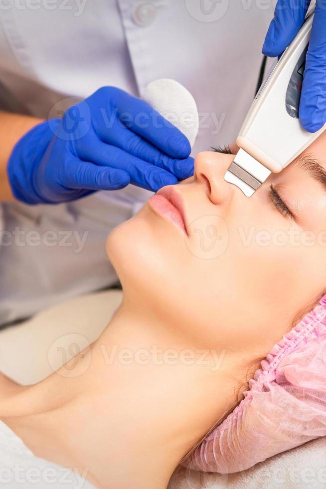 Closeup of beautiful young woman receiving ultrasound facial exfoliation and cavitation facial peeling with ultrasonic equipment in cosmetology office. photo