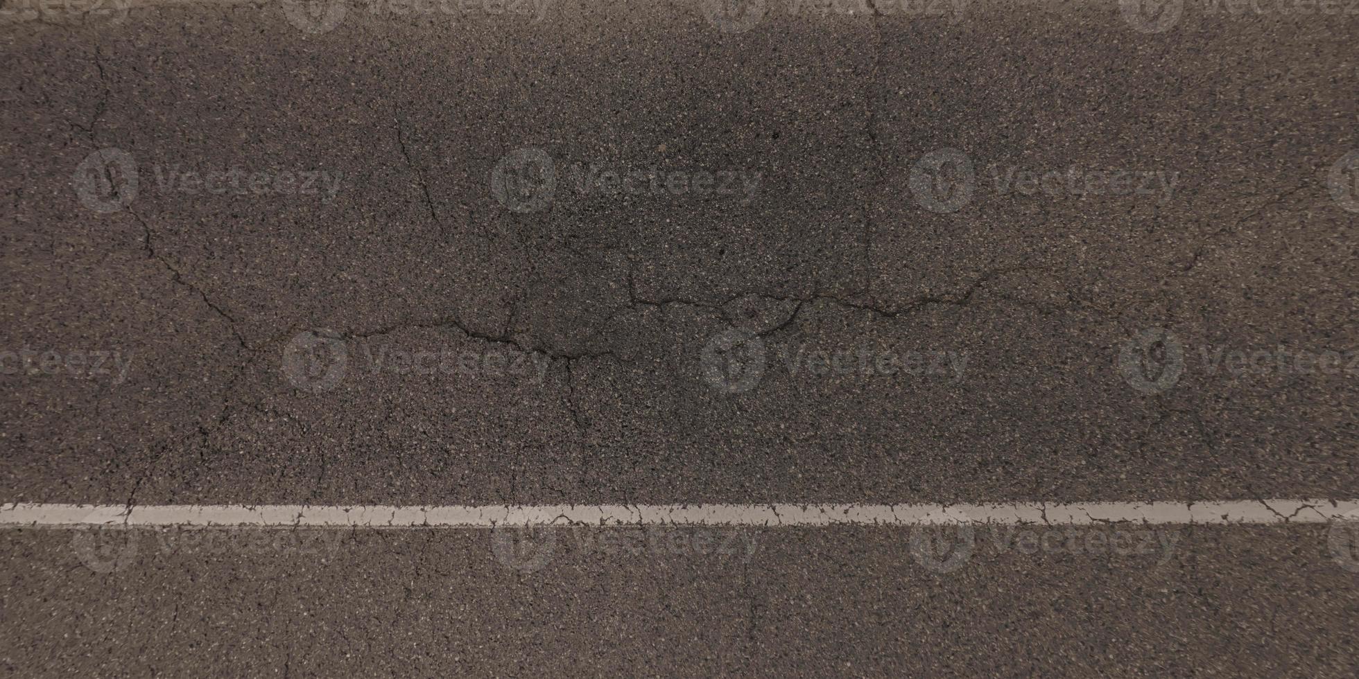 top view of surface of asphalt road made of small stones and sand with cracks photo