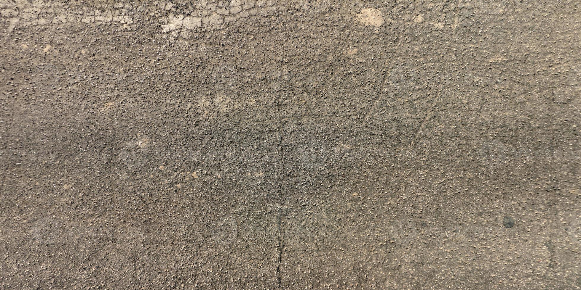 top view of surface of asphalt road made of small stones and sand with cracks photo