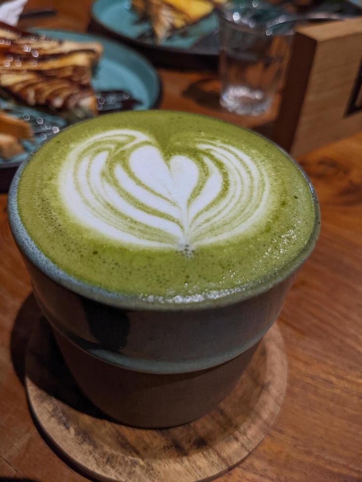 cerca arriba verde matcha latté terminado el de madera mesa en el café y resto. el foto es adecuado a utilizar para café tienda fondo, menú póster y matcha contenido medios de comunicación.