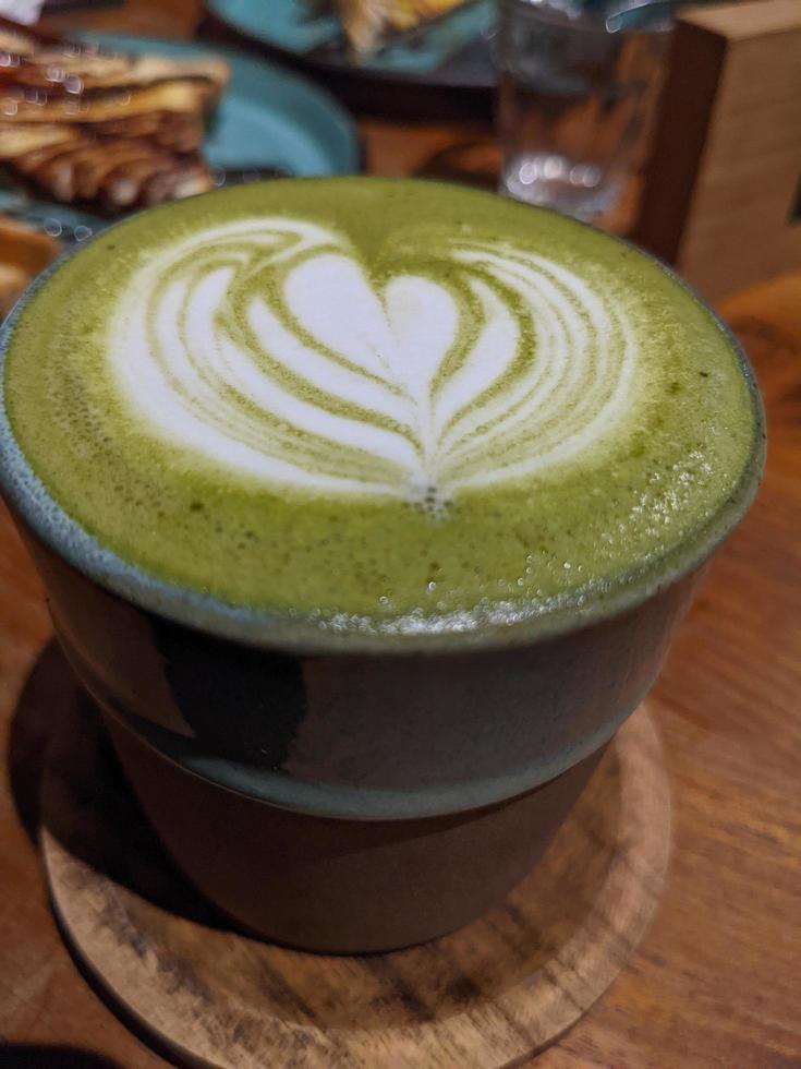 cerca arriba verde matcha latté terminado el de madera mesa en el café y resto. el foto es adecuado a utilizar para café tienda fondo, menú póster y matcha contenido medios de comunicación.