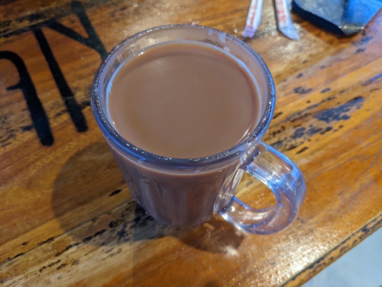 Close up photo of milk tea over the wooden table. The photo is suitable to use for coffee shop background, menu poster and coffee content media.