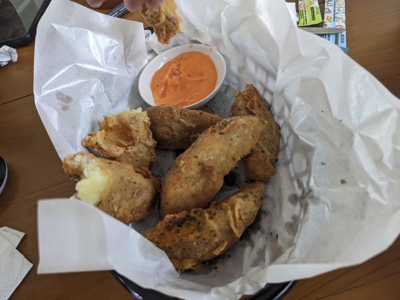 Potato wedges with cheese sauce over the white papers. The photo is suitable to use for food background, poster and food content media.