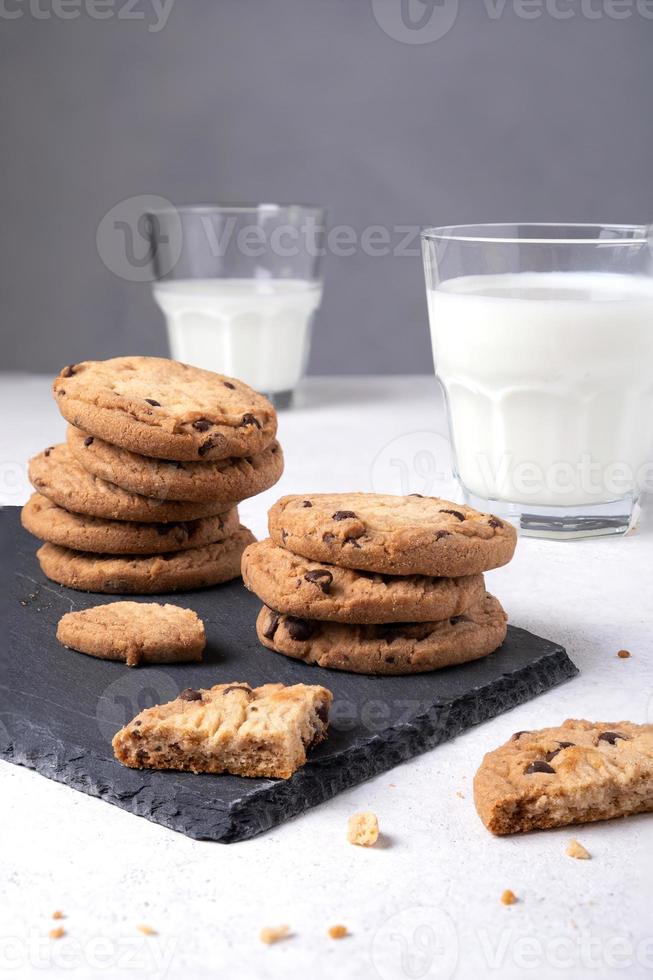 Oatmeal chocolate chip cookies on a slate serving board and milk photo