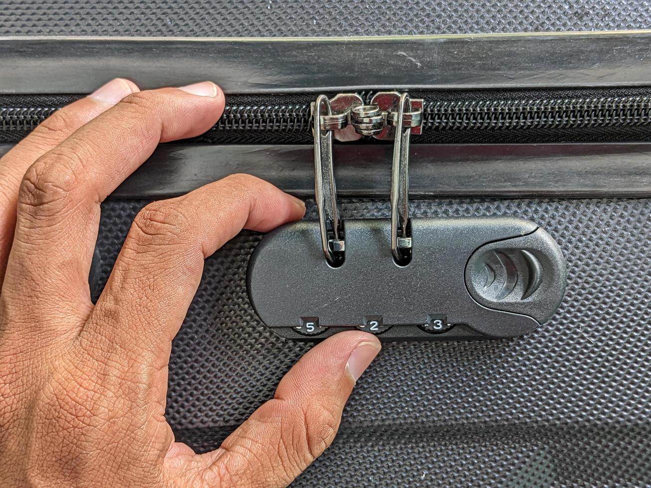 man hands unlocking a code padlock on a suitcase photo