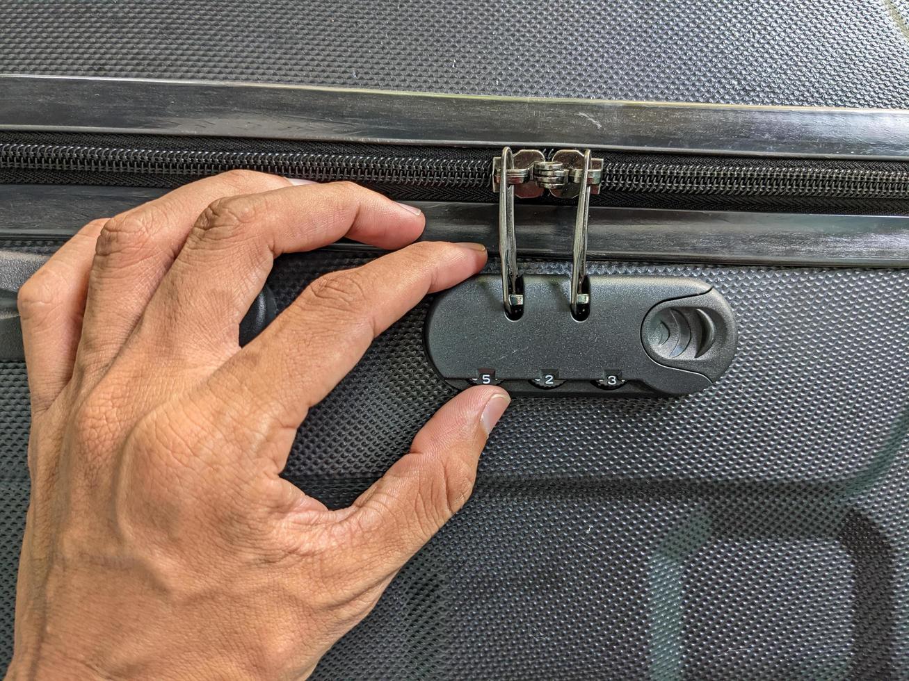 man hands unlocking a code padlock on a suitcase photo