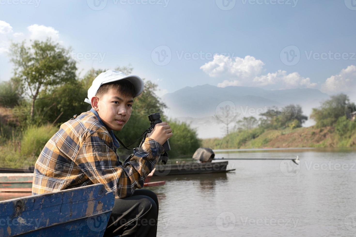 Asian boys using binoculars to do the birdwatching in tropical forest during summer camp, idea for learning creatures, wildlife animals and insects outside the classroom. photo