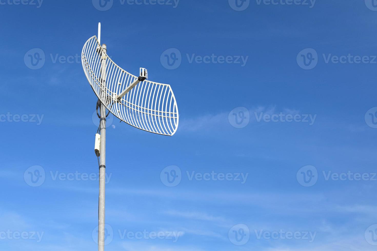 Internet wireless wifi receiver and repeater installed on metal pole on the roof of the building to service internet to users in local village, soft and selective focus. photo