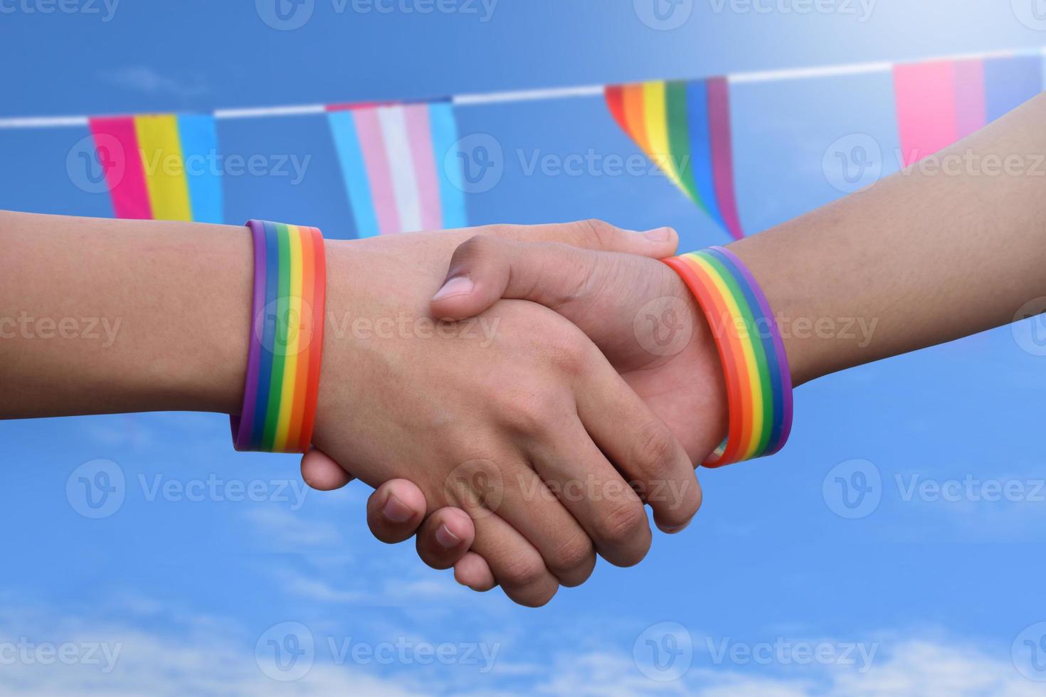 Closeup view of handshaking of LGBT people with blurred rainbow background, concept for success, cooperation, reconciliation, trust, and love for LGBT people and celebrations in pride month. photo