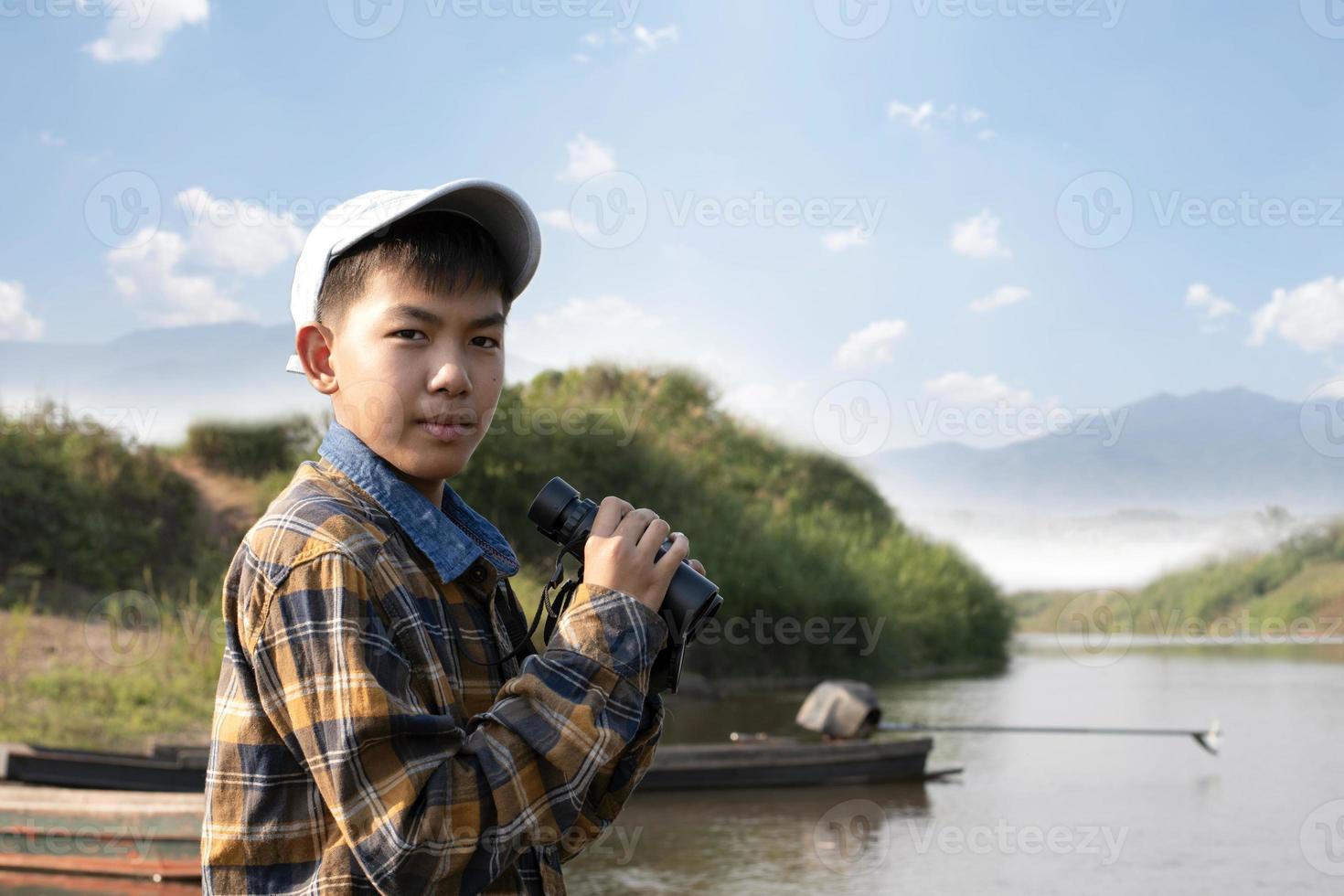 Asian boys using binoculars to do the birdwatching in tropical forest during summer camp, idea for learning creatures, wildlife animals and insects outside the classroom. photo