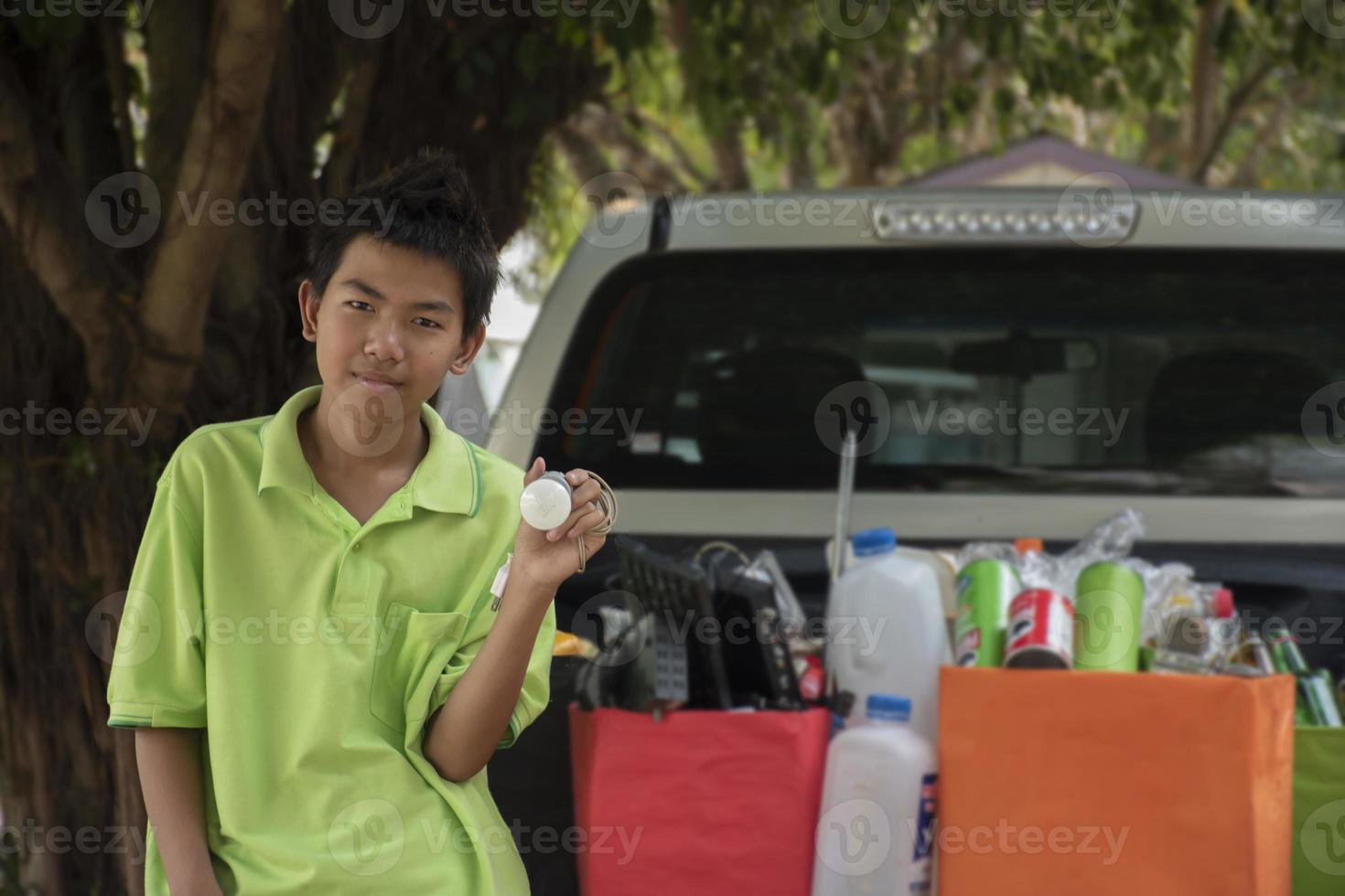Asian boys are separating garbages and putting them into the boxes in front of them near building, soft and selective focus, environment care, community service and summer vacation activities concept. photo