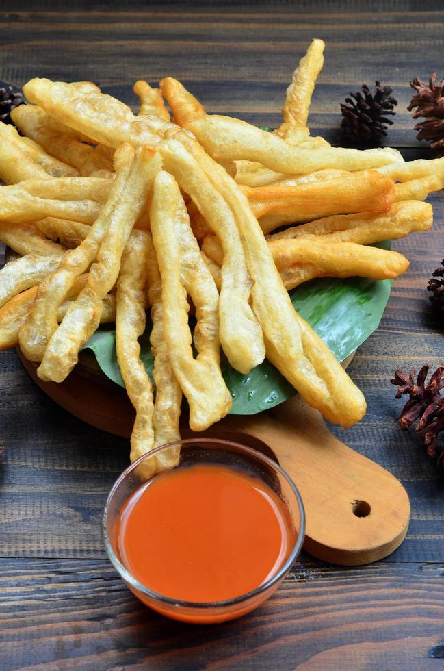 A plate of Cakwe or Cakue with chilli sauce at wooden table. Cakwe is a popular traditional snack from Chinese and indonesia photo