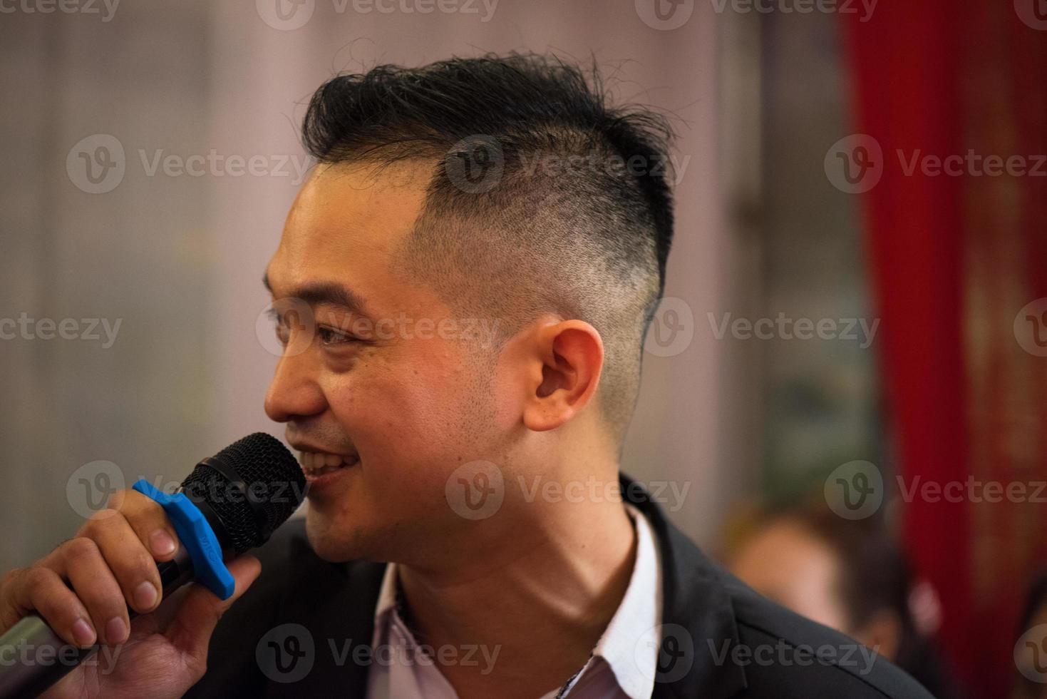 Smart smiling businessman speech, talking with a microphone in seminar conference meeting hall or restaurant, selective focus. photo