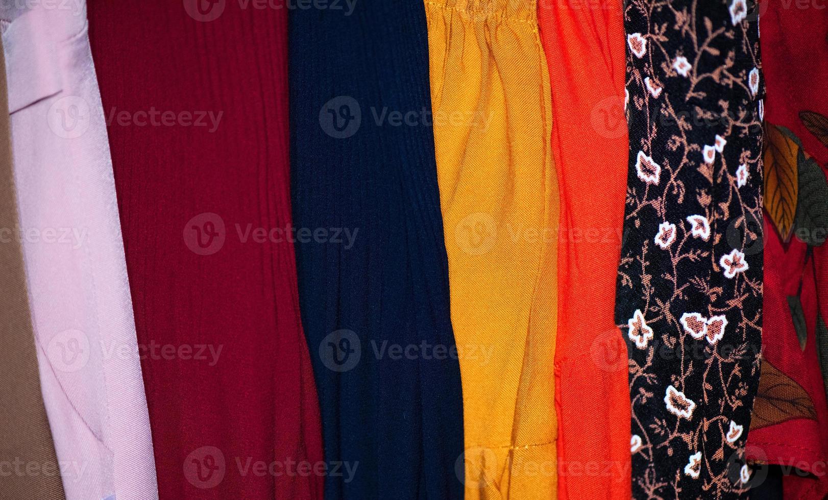 Rows of colourful silk scarfs hanging at a market photo