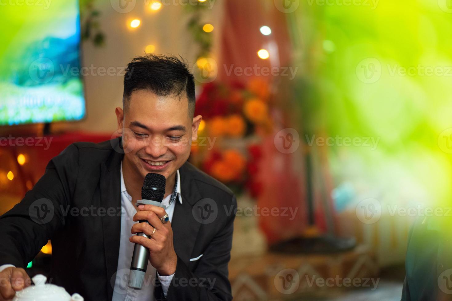 Smart smiling businessman speech, talking with a microphone in seminar conference meeting hall or restaurant, selective focus. photo