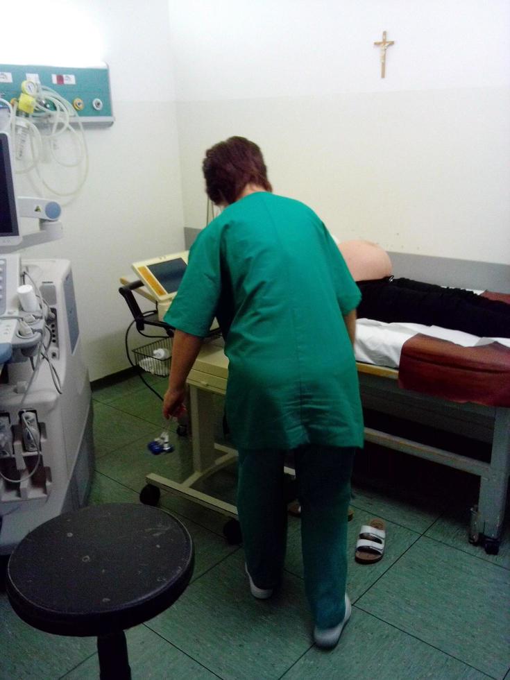 Female nurse setting up iv drip while treating senior man in hospital bed. Aged sick patient lying in bed at hospital ward with medical worker taking care and giving medication photo