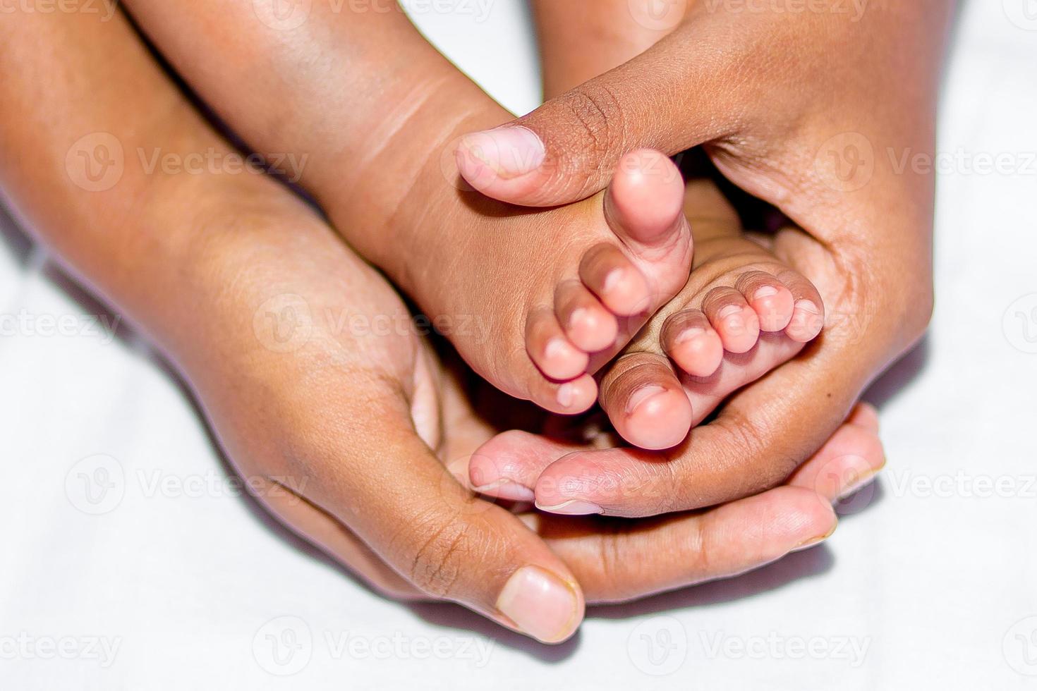 The soft legs of a baby placed on the palm of the mother's two hands on a white background. photo