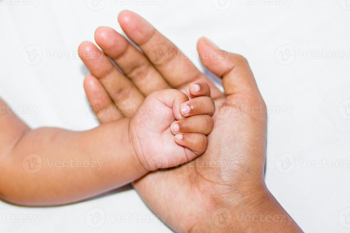 A new born baby's soft hand on mother's hand on a white background. photo
