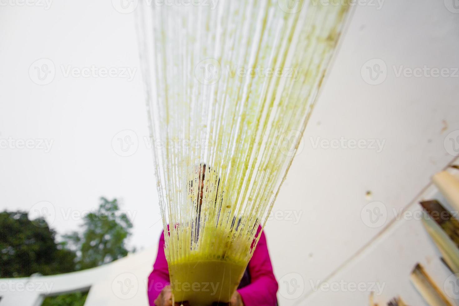 A female worker is processing the fibers of a banana tree through a fiber extraction machine. Rubber fiber of banana tree. Agricultural waste product. photo