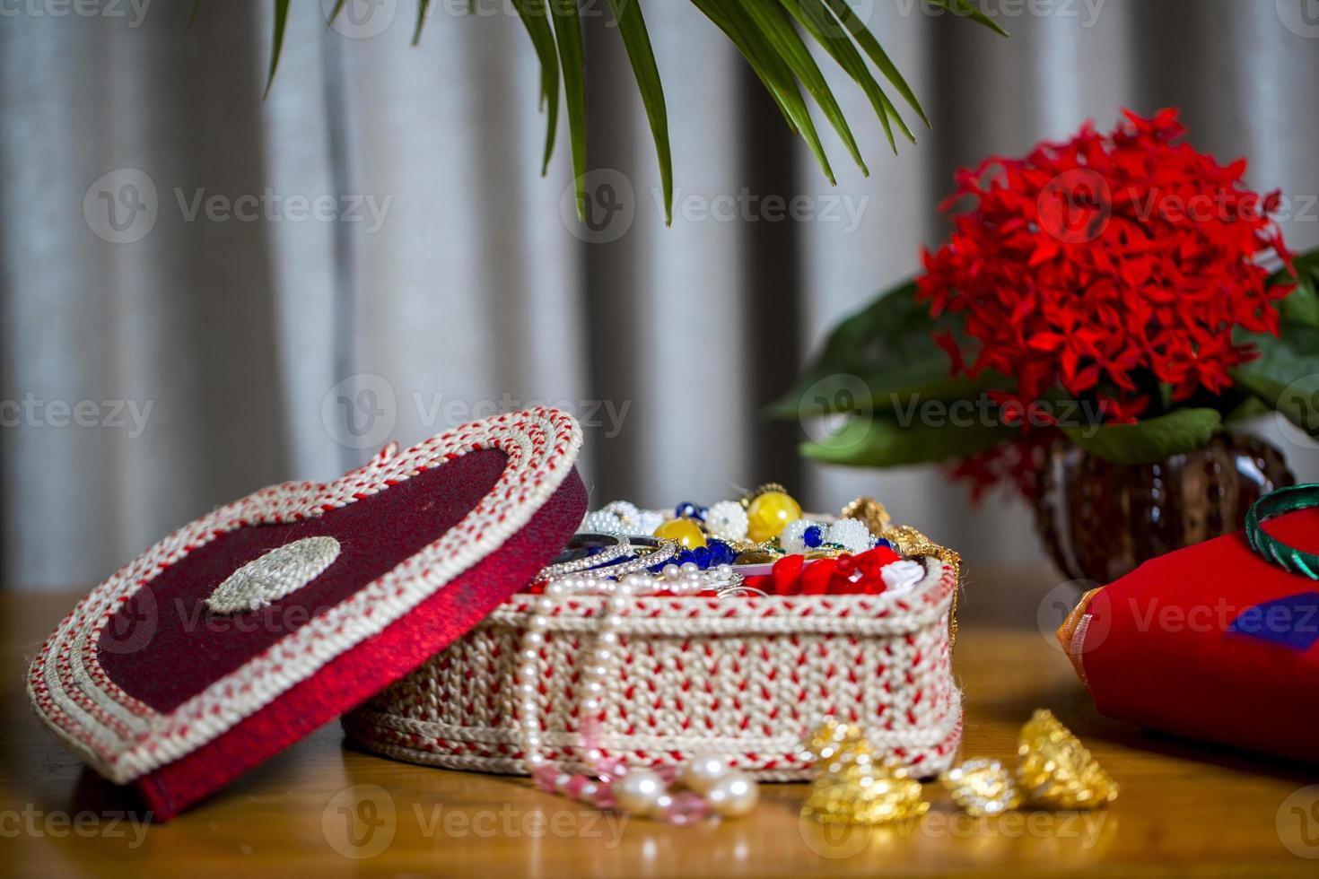 Handmade fiber ornaments box with traditional jewelry on the wooden table. Indian traditional jewelry and Bridal saree. photo