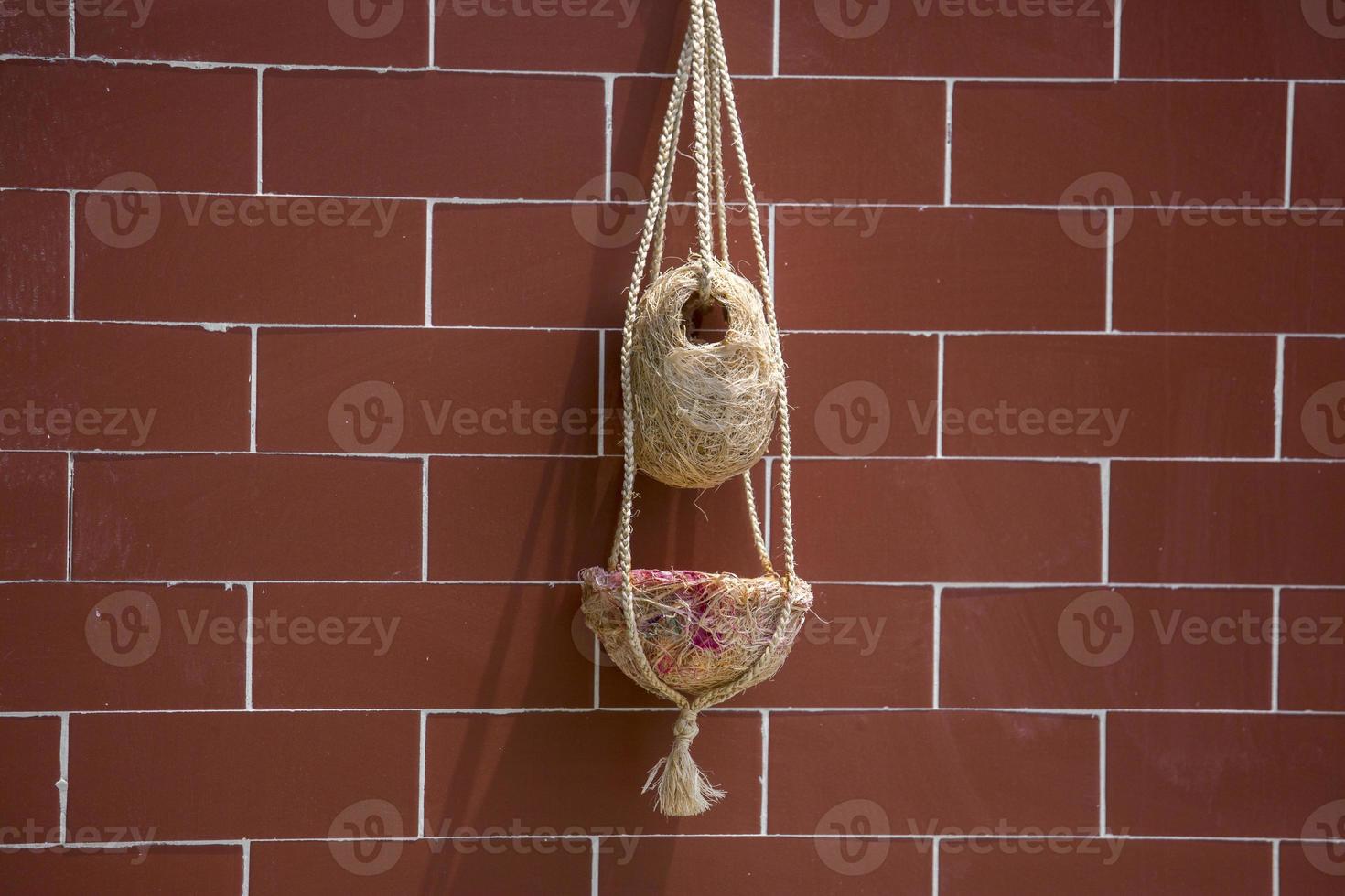 Handmade birds nest are hanging on the bricks wall. Interior Decoration Design. Nest made of fiber. photo