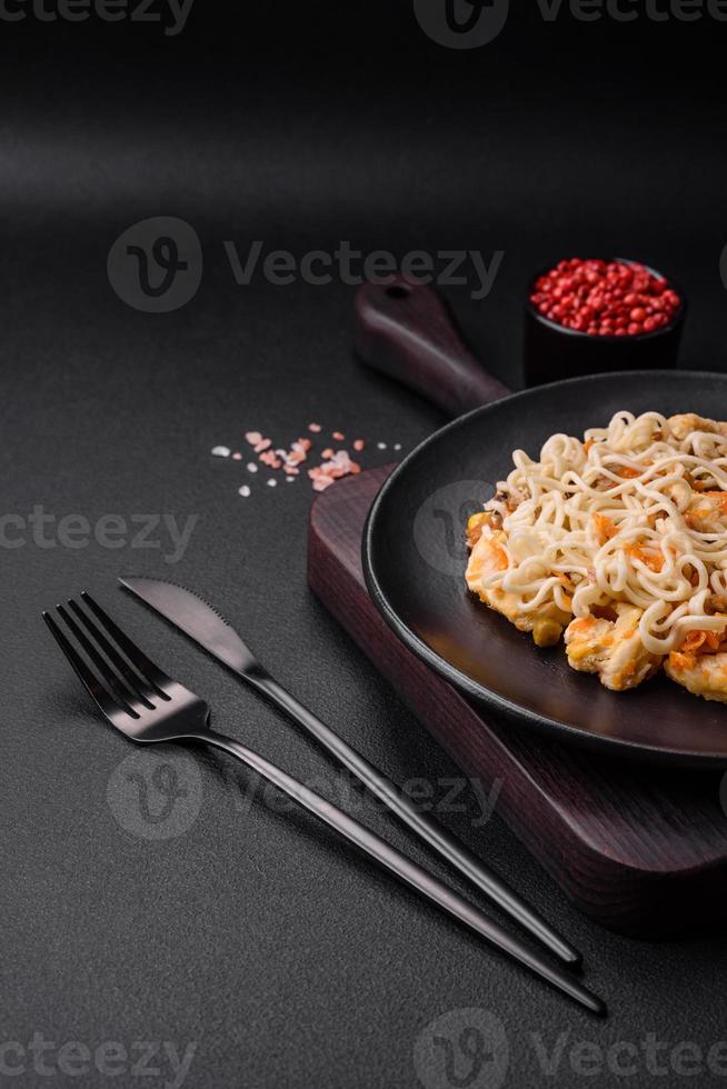 Delicious noodles with chicken and vegetables or udon on a black ceramic plate photo