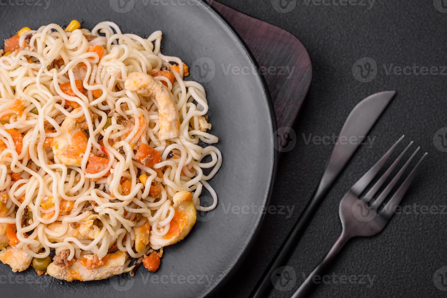 Delicious noodles with chicken and vegetables or udon on a black ceramic plate photo