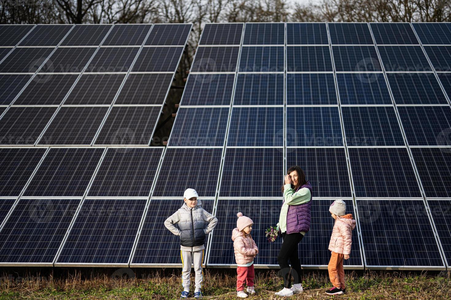 madre con Tres niños en el antecedentes de solar paneles eco energía. foto