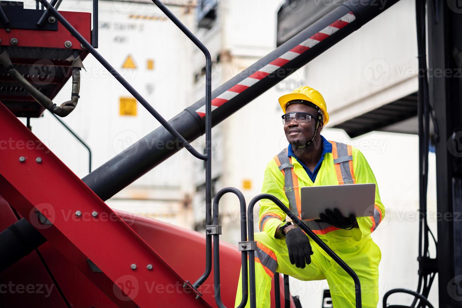 engineer man worker in safety jumpsuit uniform with yellow hardhat and use laptop computer control at cargo container ship port warehouse.transport import,export logistic industrial service photo