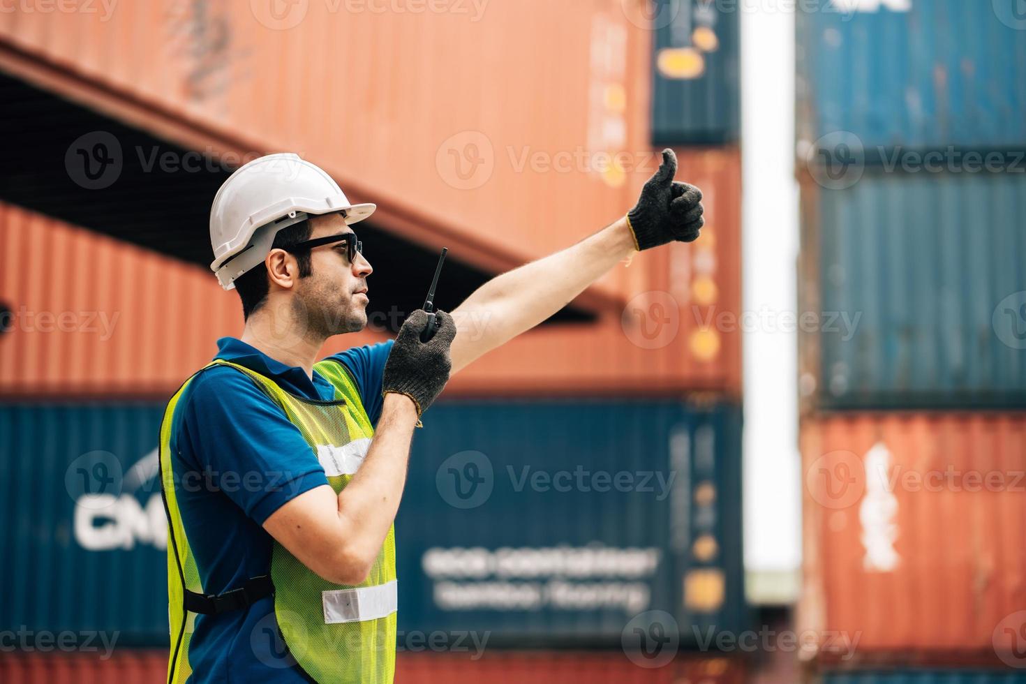 Logistics, shipping and construction worker using walkie talkie in shipyard. Transportation engineer on smartphone in delivery, freight and international distribution business in container yard photo