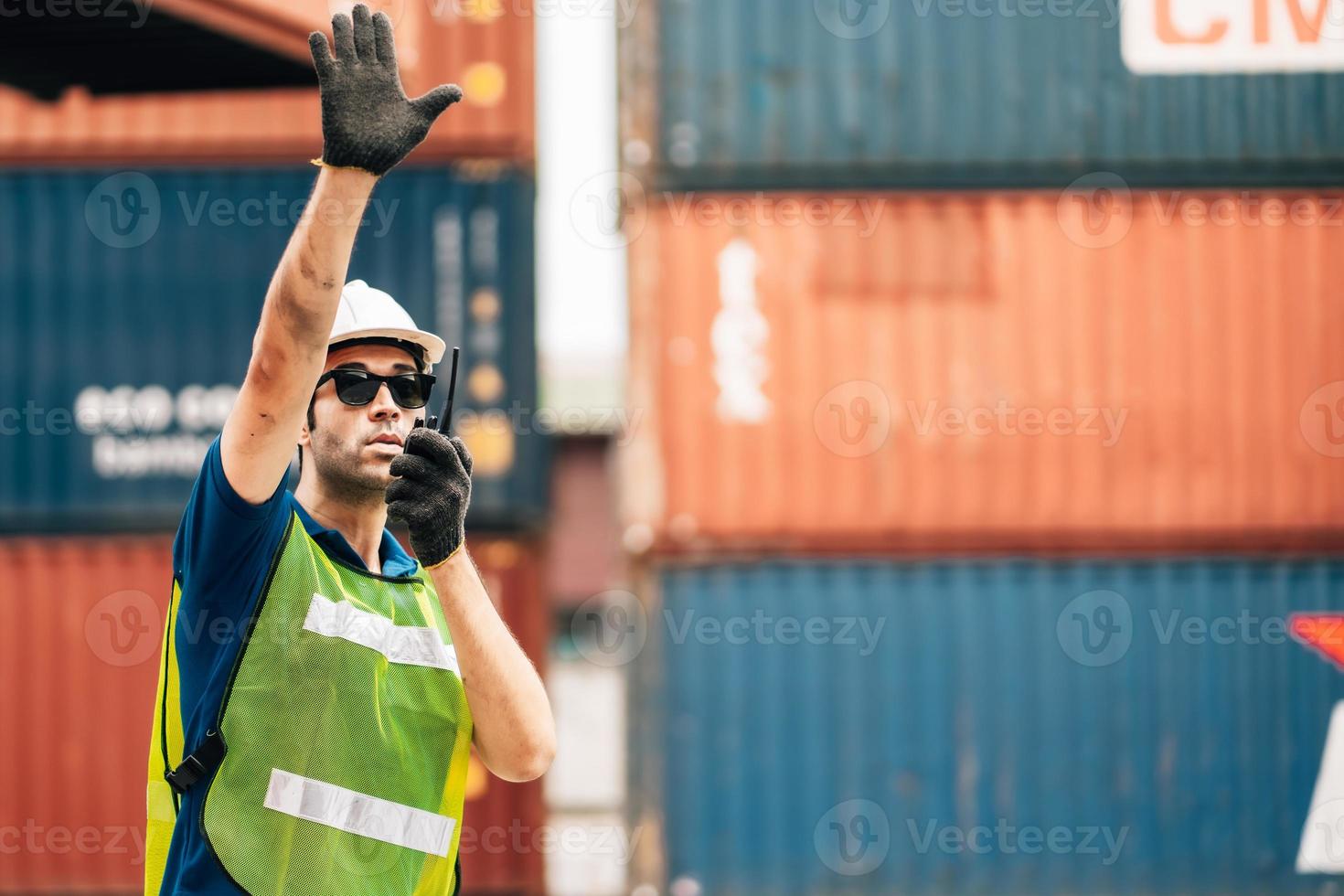 Logistics, shipping and construction worker using walkie talkie in shipyard. Transportation engineer on smartphone in delivery, freight and international distribution business in container yard photo