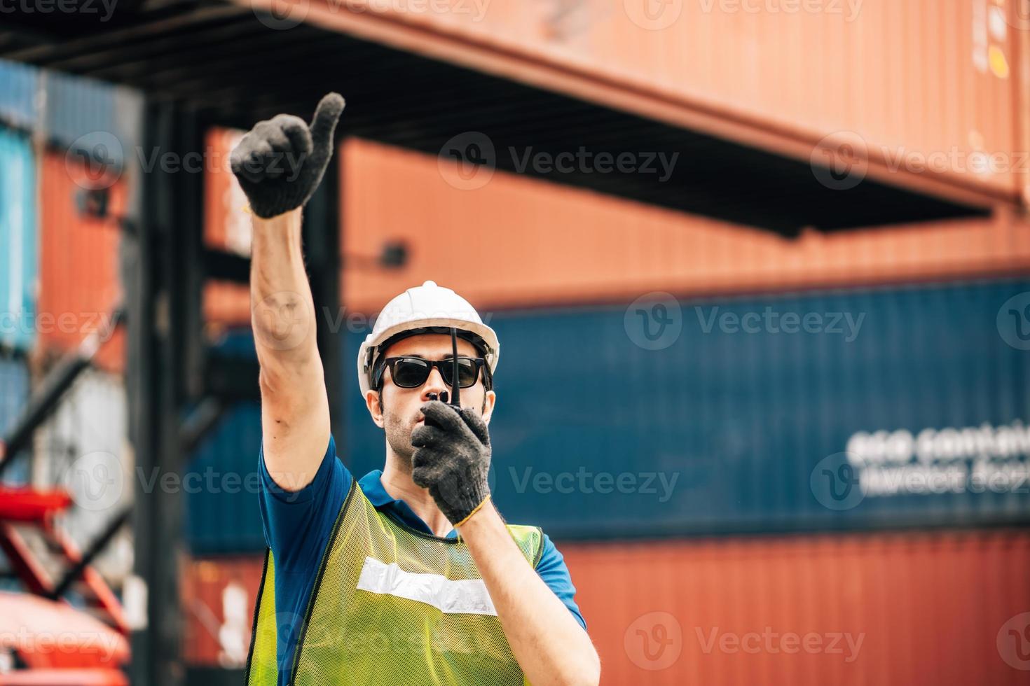 Logistics, shipping and construction worker using walkie talkie in shipyard. Transportation engineer on smartphone in delivery, freight and international distribution business in container yard photo