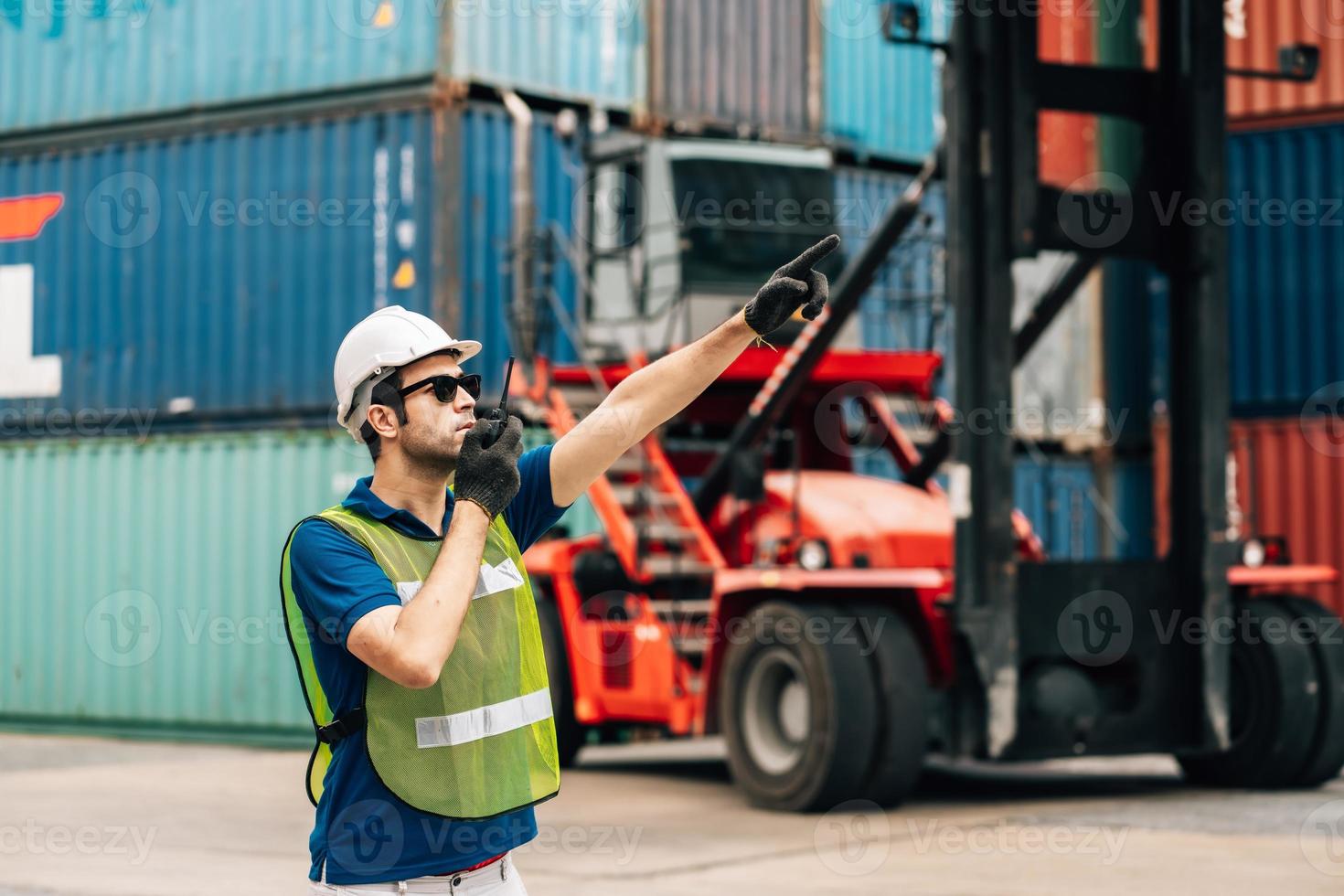 Logistics, shipping and construction worker using walkie talkie in shipyard. Transportation engineer on smartphone in delivery, freight and international distribution business in container yard photo
