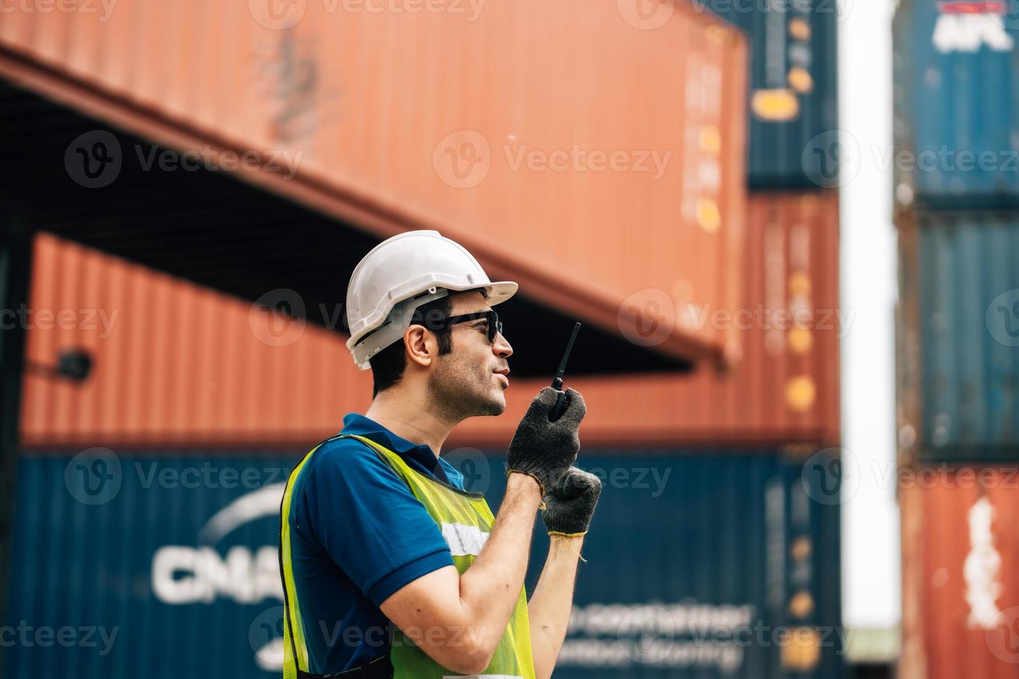 Logistics, shipping and construction worker using walkie talkie in shipyard. Transportation engineer on smartphone in delivery, freight and international distribution business in container yard photo