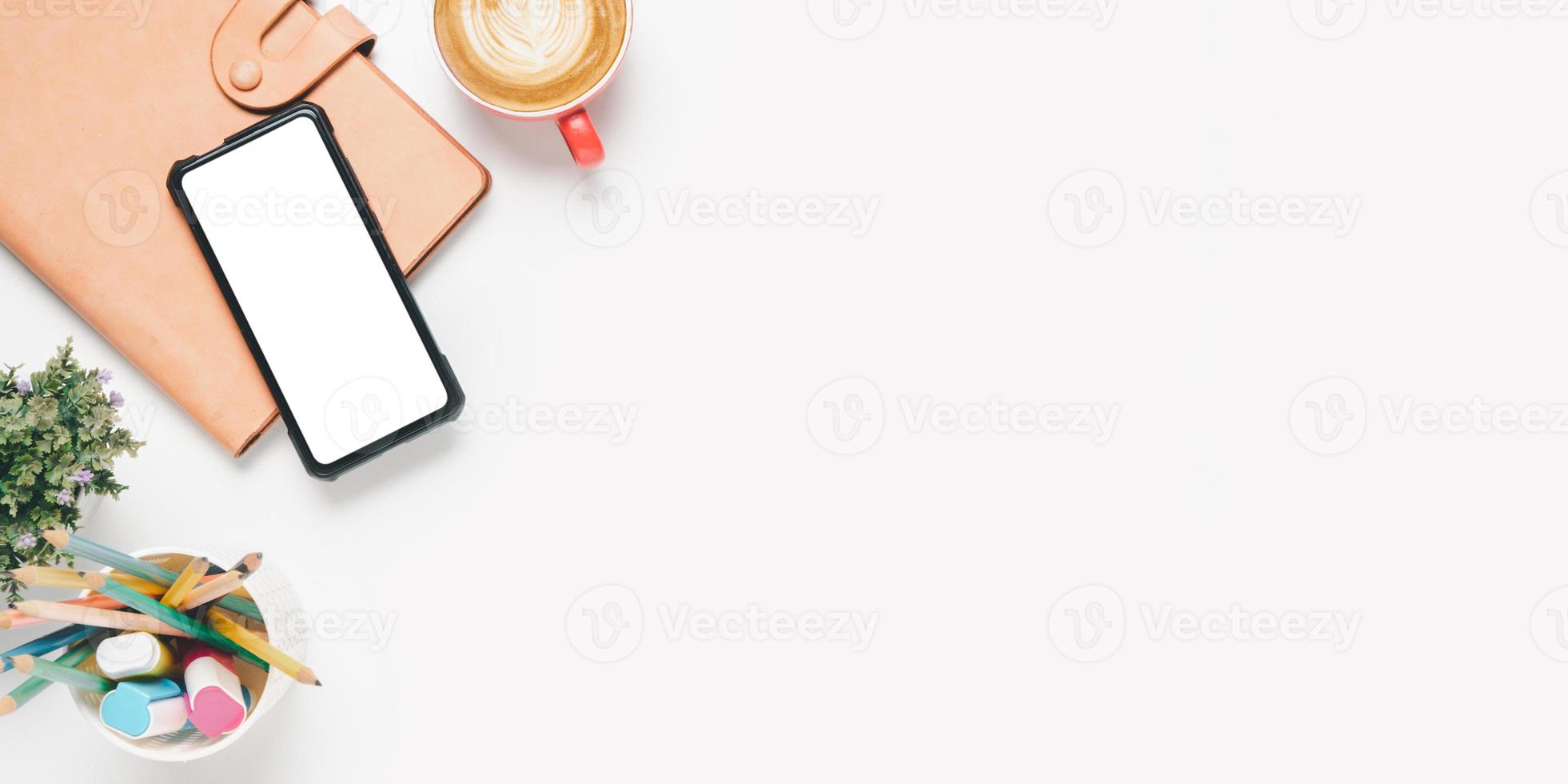 Office desk with Blank screen smart phone, Pen, Notebook, Cup of coffee on white background, Top view with copy space, Mock up. photo