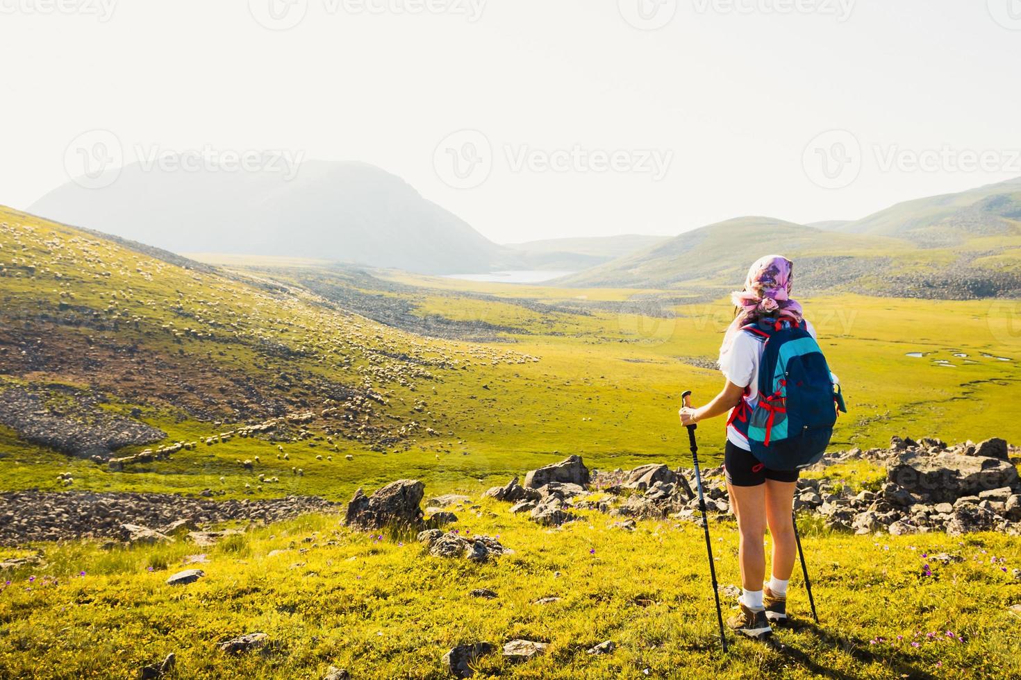 Caucasian female hiker stand enjoy panorama on hilltop on hiking trail outdoors in sunny day on Levanis lake trek in Georgia photo