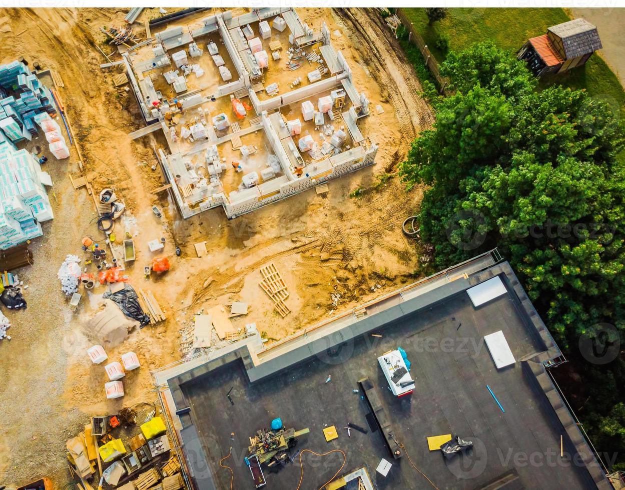 Aerial close up New Constructions real estate Development Site. Urban Construction Site, Aerial View. Rooftops and building construction site with worker laying material. photo