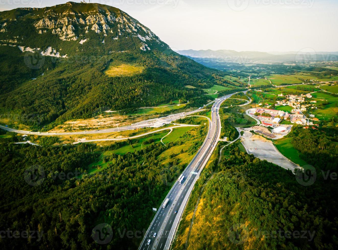 Aerial dramatic view Slovenian motorway road with lorry and cars with green meadow summer fields forest around in central Europe photo