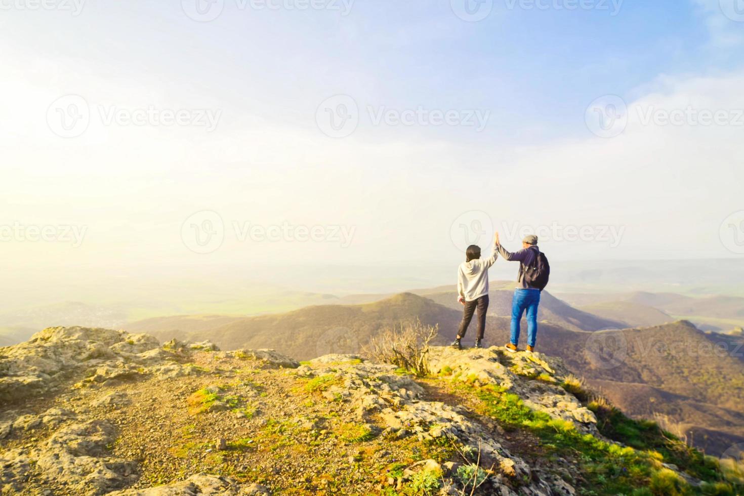 Caucasian young travelous couple enjoy mountain top viewpoint panorama together after reaching top. Hands up clapping for success, freedom and happy travels Holiday vacation photo