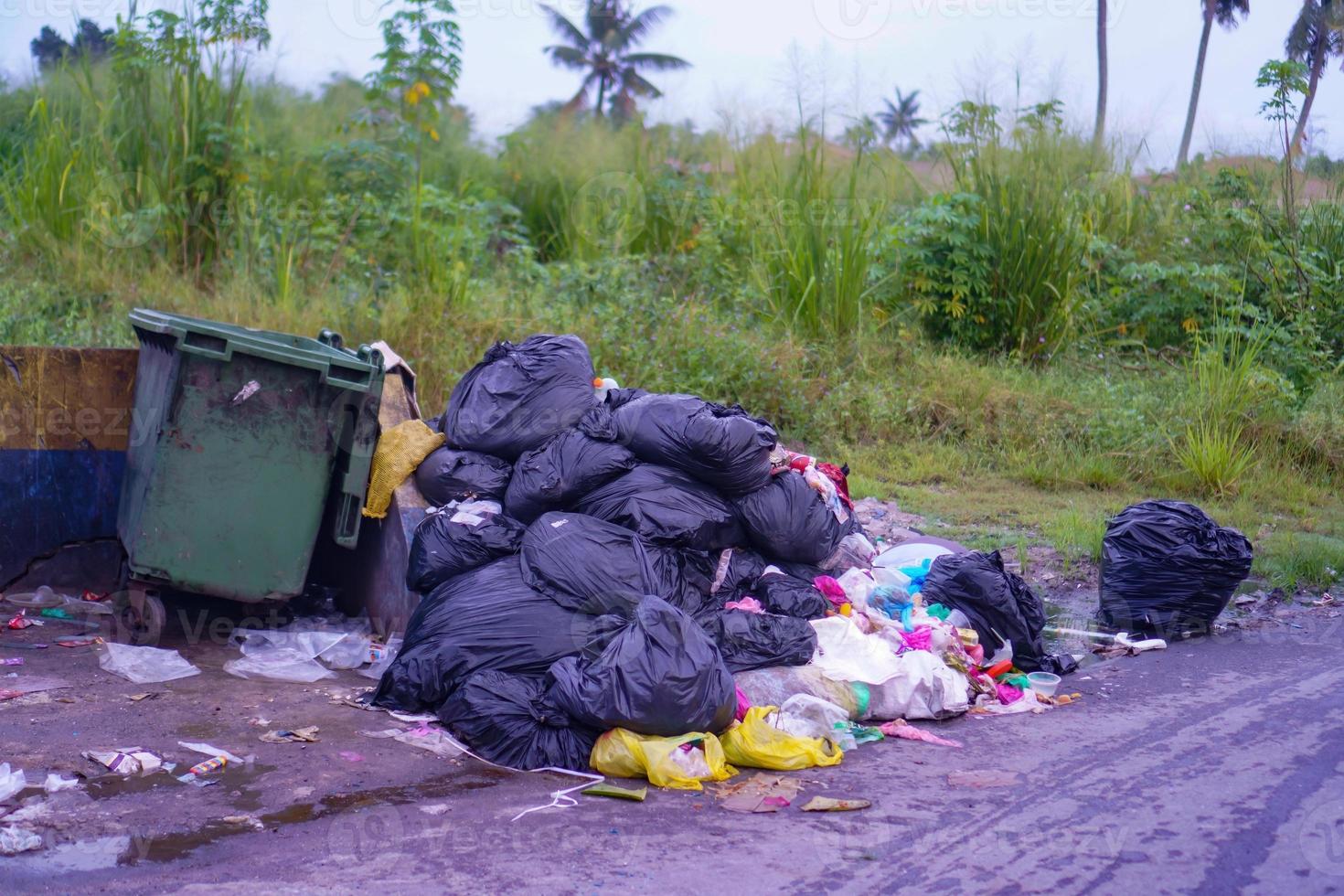 Black rubbish bag stack together beside the dustbin photo