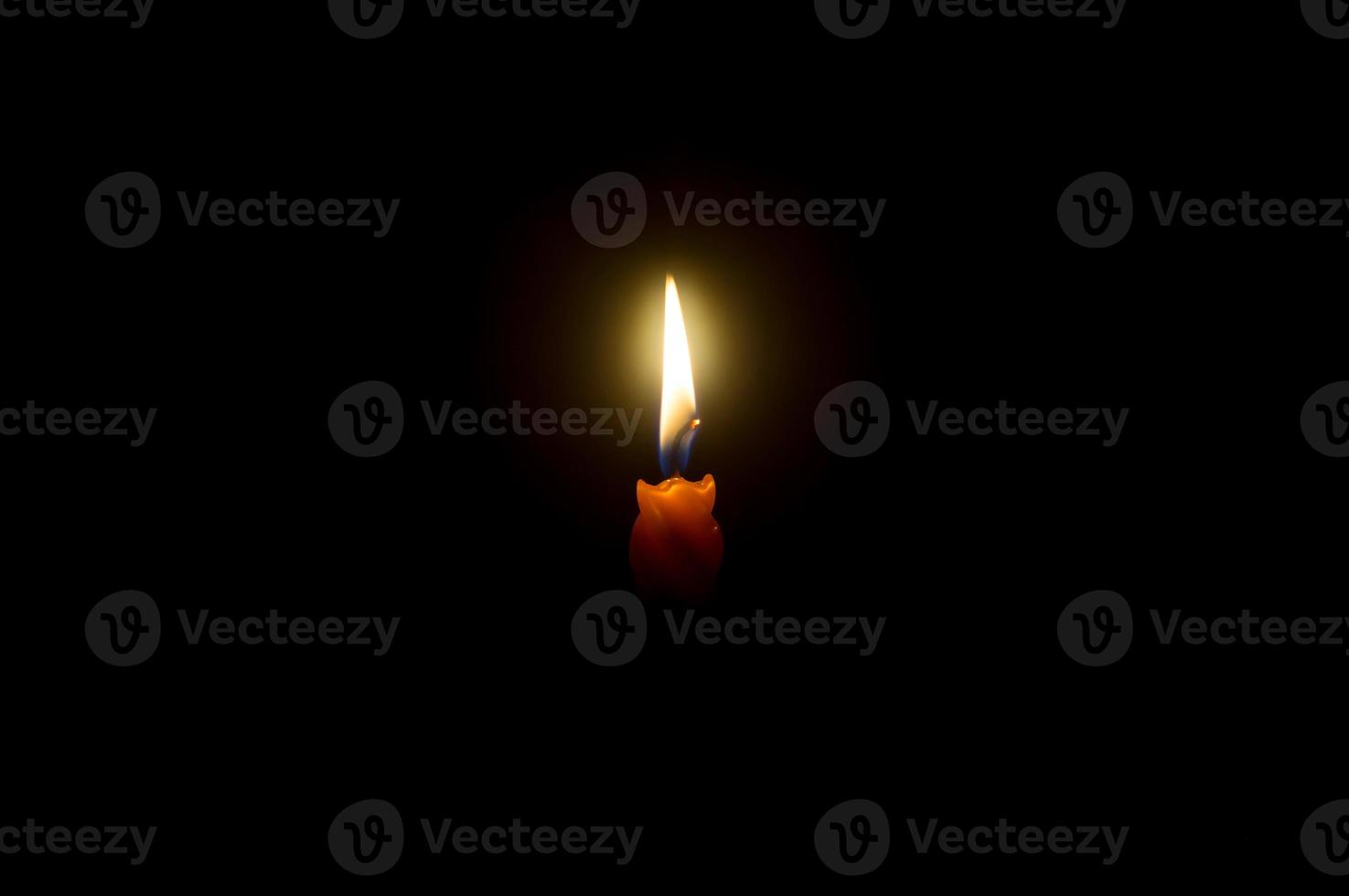 A single burning candle flame or light glowing on a spiral orange cand photo
