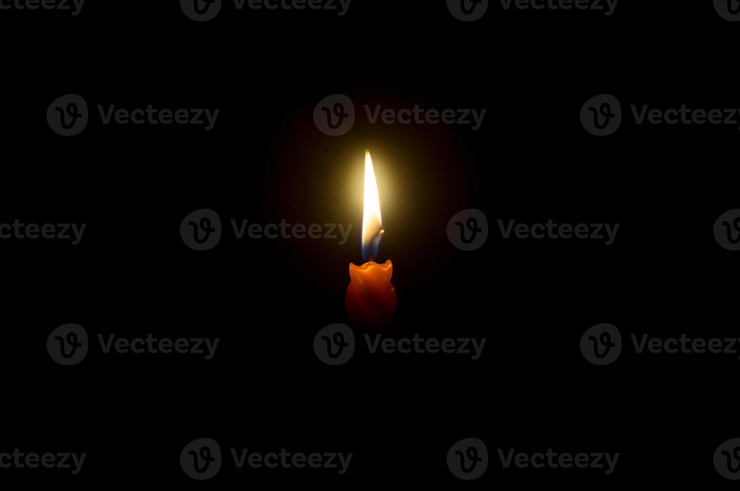 A single burning candle flame or light glowing on a spiral orange cand photo